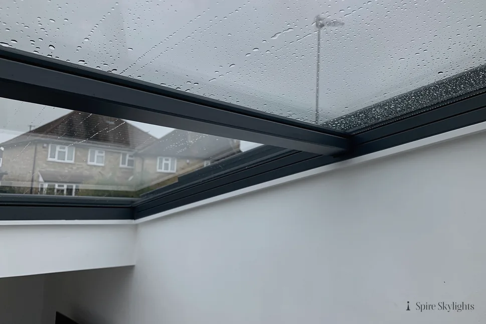 Rain on a frameless rooflight, seen from below with neighbouring houses beyond