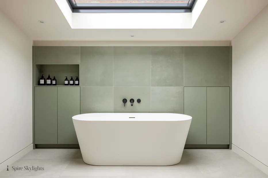 Freestanding bath under a flat rooflight in a sage-green bathroom